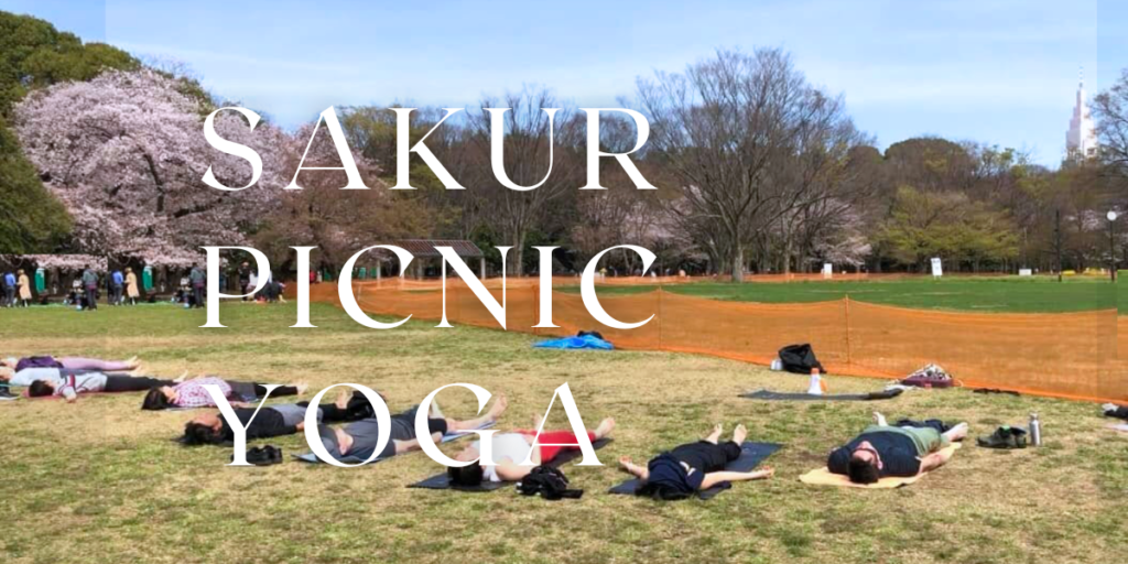 Yoga students practicing together during a Hanami Picnic Yoga event at Yoyogi Park in Tokyo