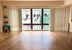 Interior of New York Style YOGA studio in Shibuya, Tokyo, featuring wooden floors, large windows, and the studio logo.