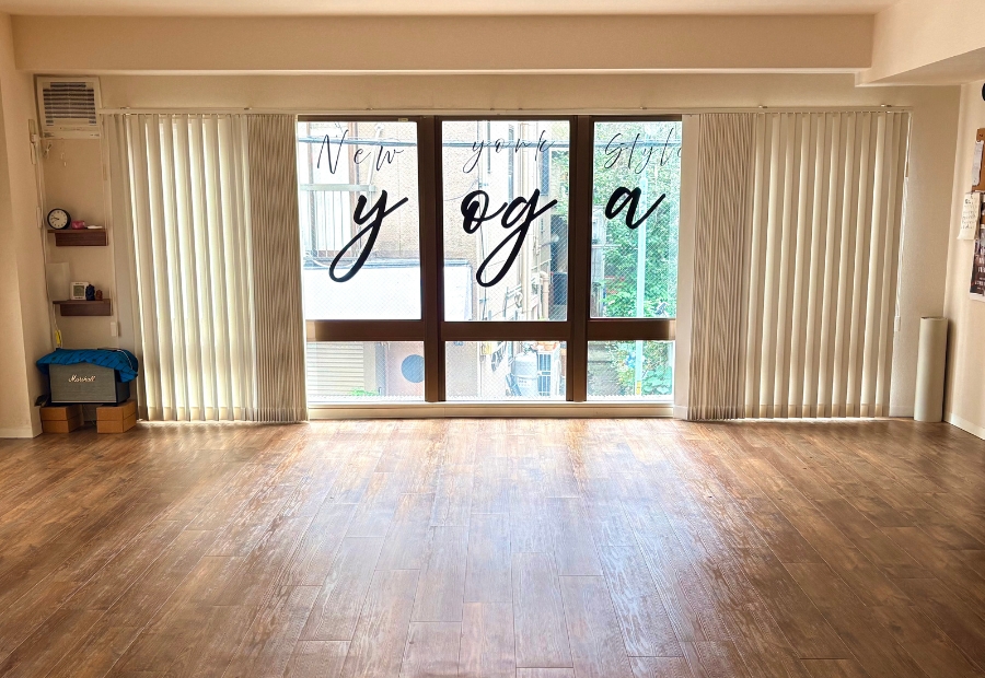 Interior of New York Style YOGA studio in Shibuya, Tokyo, featuring wooden floors, large windows, and the studio logo.